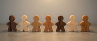 Wooden figures in various natural tones standing in a row on neutral surface, representing diversity, unity, and community connection for business and social concepts.