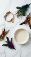 Bohemian flat lay with colorful feathers, gold bracelet and ceramic bowl on white marble background for creative projects and lifestyle design.