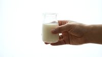 Close-up of a hand holding a glass of milk against a white background. Suitable for dairy, nutrition, and beverage advertising.