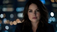 Young woman with long dark wavy hair and olive complexion wearing black blazer against blurred city lights at night, suitable for corporate, business, and professional portraits.