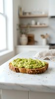 Fresh avocado toast with herbs on rustic bread slice in bright modern kitchen setting for healthy breakfast and lifestyle content.