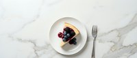 Slice of cheesecake topped with fresh berries on white plate with fork on marble surface for dessert menu and bakery advertising.