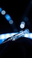 Medical syringe with needle on dark surface with blue bokeh lights background for healthcare and vaccination concepts.