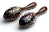 Wooden maracas with intricate floral folk art painting in blue, silver and gold tones on dark brown background, traditional musical percussion instruments.