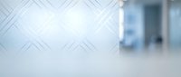 Frosted glass partition with geometric pattern in modern office corridor, blurred interior background for corporate and commercial design projects.