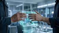Two businesspeople exchange glowing digital data between their hands in a modern office, representing technology transfer, collaboration, and innovation in corporate environments.