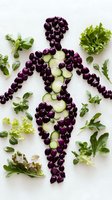Female silhouette made from fresh purple grapes and cucumber slices on white background, surrounded by green lettuce leaves and herbs for healthy eating concept.