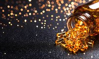 Omega-3 fish oil capsules spilling from glass bottle on dark background with golden bokeh lights, nutritional supplement concept for health and wellness.