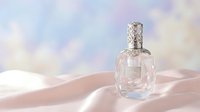 Elegant glass perfume bottle on soft pink silk fabric with dreamy pastel background for luxury cosmetics and fragrance advertising campaigns.