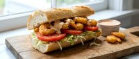 Gourmet sandwich with crispy chicken, fresh vegetables and sauce on rustic wooden board. Perfect for restaurant menus, food blogs and culinary marketing.