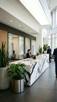 Modern office reception area with marble desk, professional woman receptionist, businessman, plants, natural light from skylights and windows in contemporary workspace.