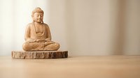 Wooden Buddha statue in meditation pose on natural wood base against neutral beige background. Peaceful zen decor for mindfulness and spiritual spaces.