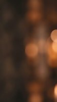 Warm bokeh lights create soft, blurred amber and golden circles against dark brown background, ideal for festive, holiday, and celebration design projects.
