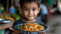 Young Asian boy smiling while holding plate of colorful stir-fried vegetables and noodles, representing healthy eating habits and family dining culture.