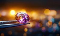Pink sapphire or precious gemstone on tweezers with blurred golden bokeh background, macro jewelry photography showing brilliance and clarity of cut stone.