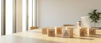 Wooden blocks with business icons arranged on office desk near window with natural lighting for corporate strategy and planning concepts.