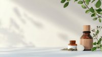 Minimalist wellness composition with essential oil bottle, dried herbs, and green leaves casting soft shadows on white background. Natural spa concept.