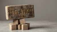 Wooden block stamped with inflation text balanced on stacked cubes, symbolizing economic pressure and rising costs for business and finance concepts.