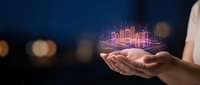 Person holding glowing neon cityscape hologram in hands against dark blue background. Digital urban development and smart city technology concept for business presentations.
