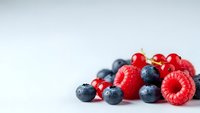 Fresh mixed berries with ripe red raspberries and juicy blueberries on clean white background for healthy eating and nutrition concepts.