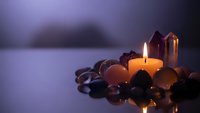 Spa wellness setup with burning candle, healing crystals and gemstones creating peaceful meditation atmosphere for relaxation and spiritual healing.