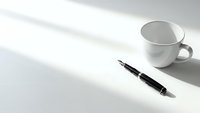 Minimalist workspace with black fountain pen and white coffee cup on clean desk surface with natural window light shadows for office productivity.