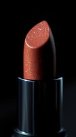 Sparkling coral lipstick with glitter particles on black background, macro photography showing texture and shimmer detail in luxury cosmetic product.
