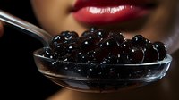 Black caviar on silver spoon with red lips in background, luxury gourmet food close up on dark setting, exclusive delicacy serving presentation.