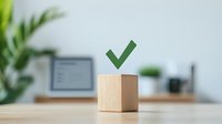 Green checkmark on wooden cube against blurred office workspace background, symbolizing approval, completion, success and positive business outcomes.