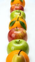 Fresh apples and oranges arranged in colorful row on white background, healthy organic fruit selection for nutrition and wellness concepts.