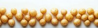 Golden round cereal balls arranged in row on white background, creating minimalist food pattern for breakfast or snack concept.