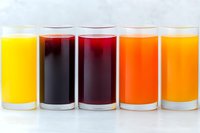 Colorful fresh juices in glasses arranged in row showing variety from yellow to red and orange. Natural healthy beverages on white background for menu design.