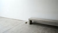 Minimalist concrete bench on polished floor in modern interior space with clean white walls creating serene architectural atmosphere for design projects.