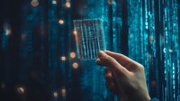 Hand holding transparent digital card against glowing blue matrix code background with bokeh light effects, representing cybersecurity and digital technology.