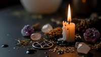 Burning candle surrounded by healing crystals, herbs and mystical symbols creating atmospheric spiritual meditation and wellness ritual scene.