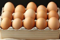 Fresh brown chicken eggs arranged in rows inside wooden container, close-up view showing natural texture and color of farm fresh eggs on rustic background.