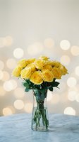 Yellow roses bouquet in glass vase on marble surface with warm bokeh lights background for romantic occasions and home decor.