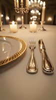 Elegant formal dining table setting with gold-rimmed plate, silver cutlery, and lit candelabras in soft focus background. Suitable for event planning, hospitality, and luxury dining concepts.