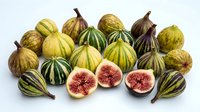 Fresh figs arranged on white background, whole and halved fruits showing pink interior flesh and seeds, ready for culinary, food styling, recipe, and ingredient design projects.