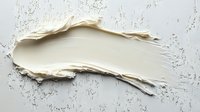Creamy white cosmetic texture smear on light surface showing smooth, luxurious consistency for beauty product photography and packaging design.
