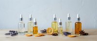 Natural aromatherapy essential oils in glass bottles with dried lavender, orange slices and spices on wooden surface for wellness and spa treatments.