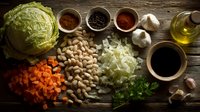 Fresh cooking ingredients arranged on rustic wooden table with cabbage, beans, carrots, onions, spices, garlic, and olive oil for healthy meal preparation.