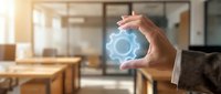 Businessman hand holding glowing gear icon in modern office space representing innovation, technology solutions, and digital transformation concepts.