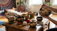 Sound healing therapy session with Tibetan singing bowls on wooden table. Meditation and wellness practice for stress relief and relaxation in peaceful home setting.