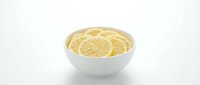 Fresh lemon slices arranged in white ceramic bowl on clean background for culinary and healthy lifestyle concepts.