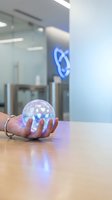 Hand holding glowing sphere with digital icons in modern office environment, representing technology, innovation, and data connectivity for business solutions.