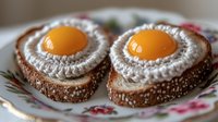 Gourmet breakfast with two sunny side up eggs on seeded bread slices, served on decorative floral plate.
