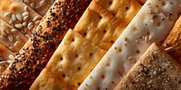 Assorted crispy crackers and breadsticks arranged diagonally, featuring sesame seeds, poppy seeds, and various seasonings for appetizers or snacks.