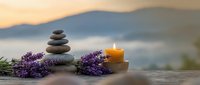 Zen spa composition with stacked stones, lavender flowers and burning candle at sunset. Relaxation, meditation and wellness concept for aromatherapy treatments.