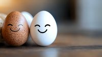 Smiling brown speckled and white eggs with drawn happy faces expressing friendship and harmony on wooden surface, concept of diversity and relationships.